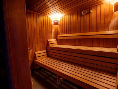 Holzsauna mit mehrstufigen Sitzbänken und warmem Licht an den Wänden.