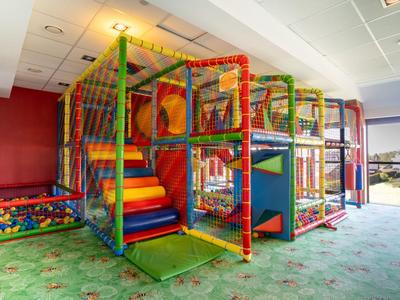 Ein moderner, bunter Indoor-Spielplatz mit Rutschen und Kletterstrukturen in einem Hotel.