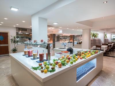 Buffetbereich mit frischem Obst und gesunden Säften in einem hellen Speisesaal eines Hotels.