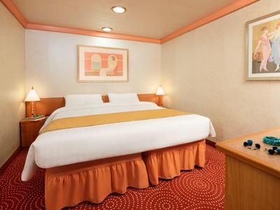 Gemütliches Schlafzimmer mit großem Bett, orangem Teppich und Bildern an den Wänden.