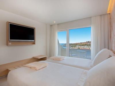 Helles Schlafzimmer mit zwei Einzelbetten, großem Fenster mit Meerblick und minimalistischem Design.