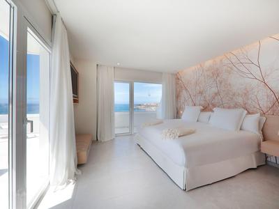 Bright bedroom with large bed, sea view, and access to a terrace