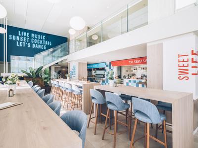 Modern café with long counter, blue chairs, and open mezzanine floor.