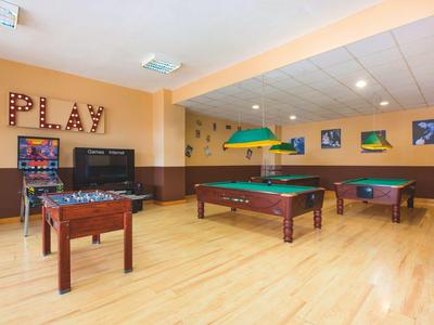 Speelkamer met pooltafels, tafelvoetbal, tv en decoratief PLAY-bord aan de muur.