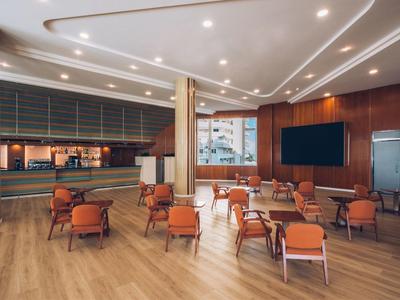 Elegant hotel lounge area with wooden floor, armchairs, and modern lighting.