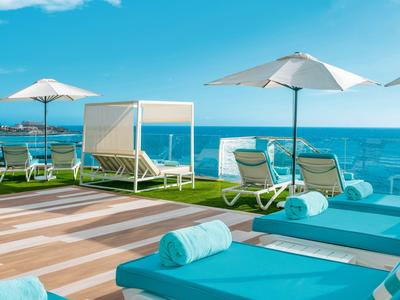 Relaxing outdoor area with sun loungers, umbrellas, and sea view under clear sky.