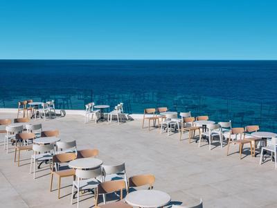 Leeg buitenterras met stoelen en tafels met uitzicht op zee onder een heldere blauwe lucht