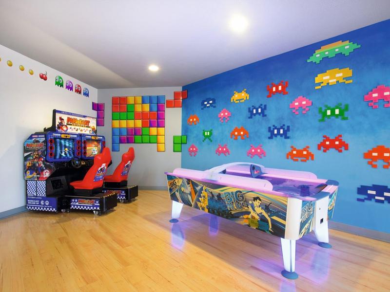 Kleurrijke speelruimte met airhockeytafel, racearcadeautomaten en videogamewand