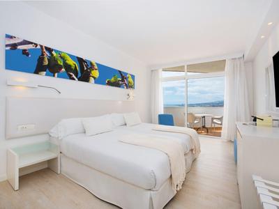 Chambre d'hôtel lumineuse avec deux lits simples, balcon et vue sur la mer.