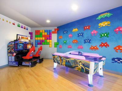 Salle de jeux colorée avec table de air hockey, bornes d'arcade de course et mur de jeux vidéo