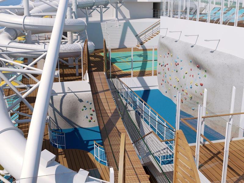 Outdoor climbing wall and water slide near the pool on a cruise ship deck.