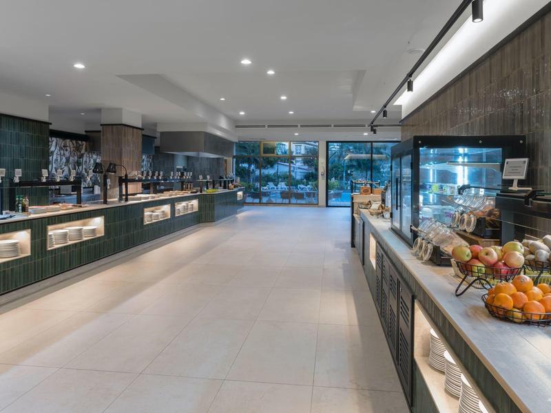Modern hotel buffet with fruit display and large glass windows overlooking outside.
