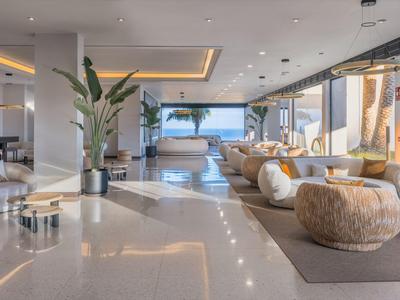 Modernes Hotellounge mit großen Fenstern, gemütlichen Sitzgelegenheiten und stilvoller Dekoration.