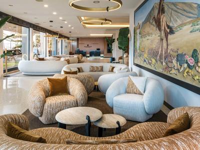 Gemütliche Lounge mit stilvollen Sesseln, Couchtischen und großer Wandkunst in hellem, offenem Raum.