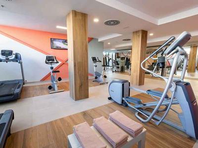 Salle de sport moderne avec divers appareils d'exercice et piliers en bois dans une pièce lumineuse