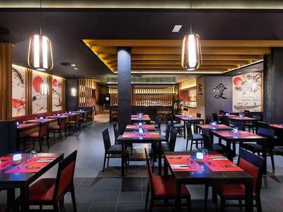 Nowoczesna restauracja z nakrytymi stołami i ciemnym drewnianym wnętrzem.