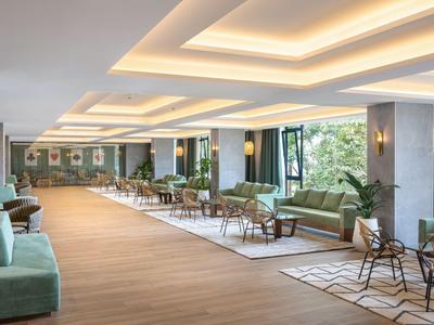 Przestronny hol hotelowy z nowoczesnymi meblami i ciepłą drewnianą podłogą.