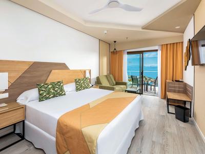 Modernes Hotelzimmer mit Doppelbett, Balkon und Blick auf das Meer.