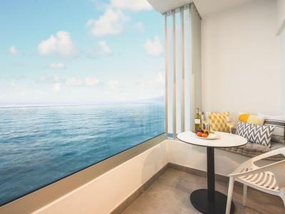 Gezellige zithoek met tafel op balkon met uitzicht op zee en blauwe lucht.