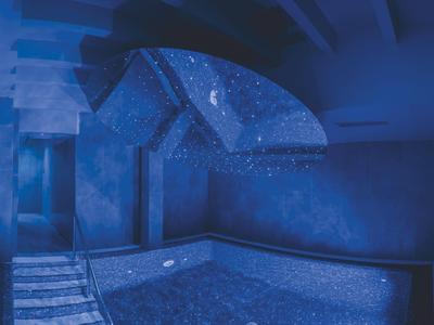 Espace détente avec un grand bain à remous et éclairage bleu dans un spa.