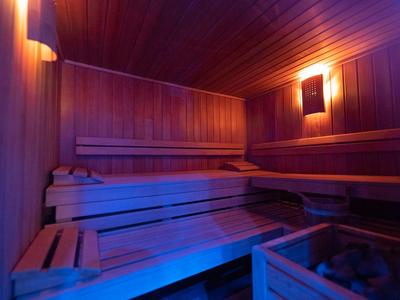Intérieur d'un sauna éclairé avec des bancs en bois et des panneaux muraux.