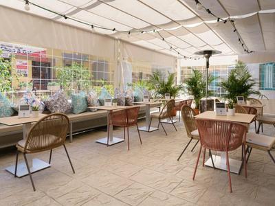 Terrasse couverte confortable avec chaises en métal et bancs rembourrés à la lumière du jour.