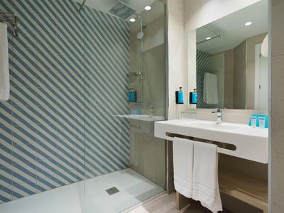 Salle de bain moderne avec douche à l'italienne et lavabo blanc avec serviettes.