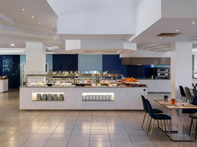 Restaurante de hotel moderno con buffet y mesas preparadas en un ambiente iluminado.