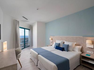 Modern hotel room with double bed, desk, TV, and balcony with a view.