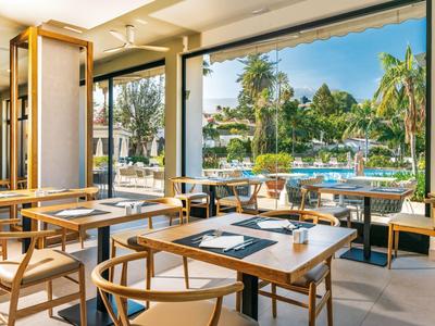 Modernes Restaurant mit Holzmöbeln und Blick auf einen Pool und Palmen