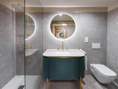 Modern hotel bathroom with round illuminated mirror and stylishly designed sink.