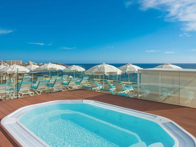 Hot tub on wooden deck overlooking beach and sea under clear sky
