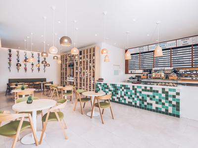 Bright café with modern wooden furniture and blue-green tiles on the counter.