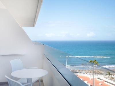 Balkon met witte tafel en stoelen met uitzicht op zee onder heldere lucht
