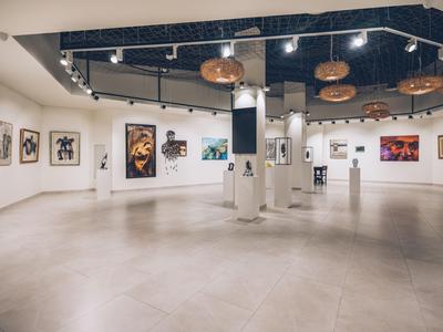 Interior moderno de galería de arte con paredes blancas y varias pinturas en las paredes.