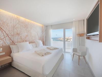 Modernes Hotelzimmer mit Doppelbett, Sitzgelegenheit und Blick auf das Meer durch das Fenster.