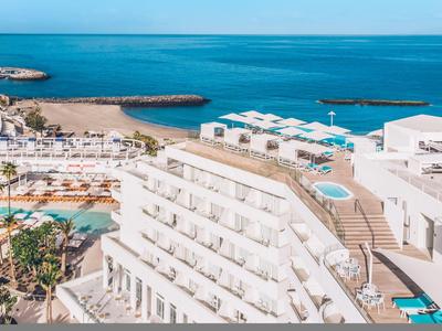 Hôtel de luxe avec piscine et vue sur la mer bleue en bord de mer.