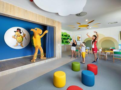Children dancing and playing in a colorful, modern playroom with a stage.