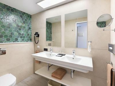 Modern bathroom with double sinks, hexagon tiles, and large mirrors.