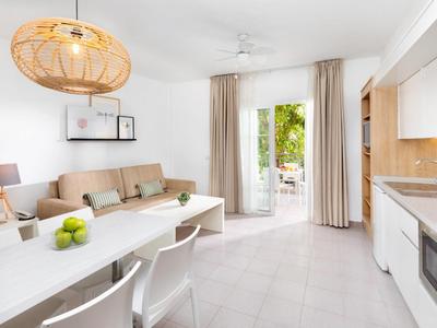 Sala de estar moderna y luminosa con comedor, sofá, cocina pequeña y acceso al balcón.