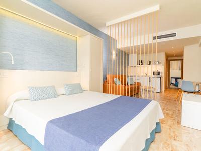 Modern hotelkamer met groot bed, blauwe en witte accenten en open ruimte ontwerp.