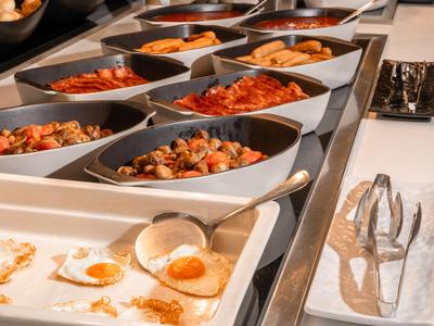 Buffet met verschillende warme gerechten waaronder gebakken eieren en groentegerechten.