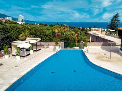 Outdoor pool on a terrace overlooking greenery and blue sky