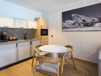 Moderne keukenruimte met een kleine ronde tafel en twee houten stoelen in een hotelkamer.