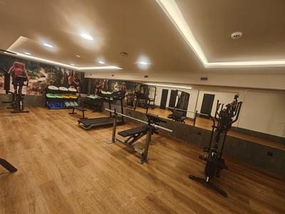 Modern uitgeruste fitnessruimte met loopbanden, gewichten en spiegels.