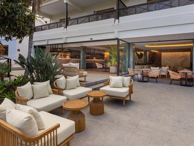 Área abierta con asientos modernos y plantas en un entorno hotelero.