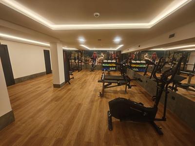 Palestra moderna con pavimento in legno, attrezzature per l'allenamento e parete a specchio.