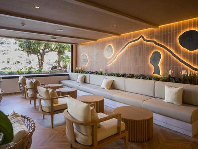 Modern hotel lounge area with comfortable chairs and sofas, illuminated by warm lighting.