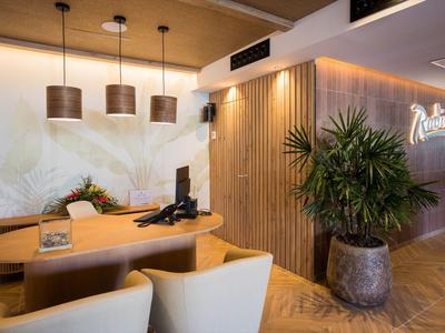 Moderne hotelreceptie met houten accenten, gezellige stoelen en groene planten.