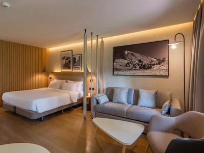 Moderne hotelkamer met bed, bank, fauteuil en stijlvolle inrichting in warme tinten.